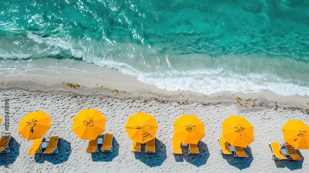 Naklejka premium A tropical beach by the sea or ocean adorned with yellow umbrellas and sun loungers on its white sands.