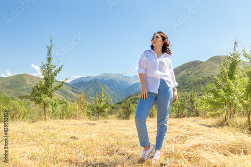 Joyful woman admiring scenic mountain landscape in blooming meadow