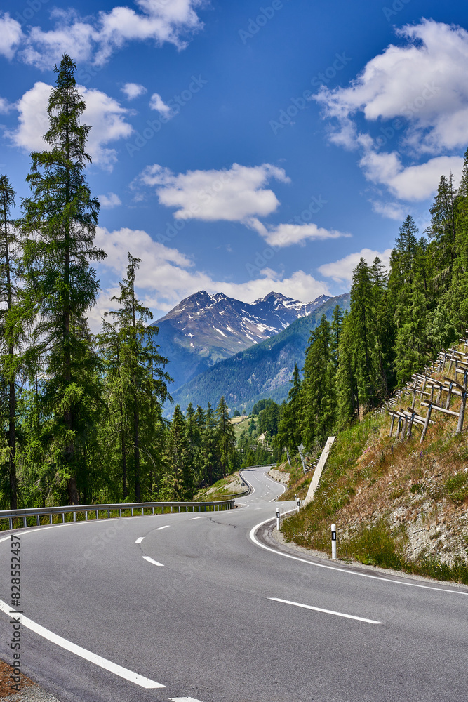 a curving road passing through the middle of the mountains on a sunny day a curving road passing through the middle of the mountains on a sunny day