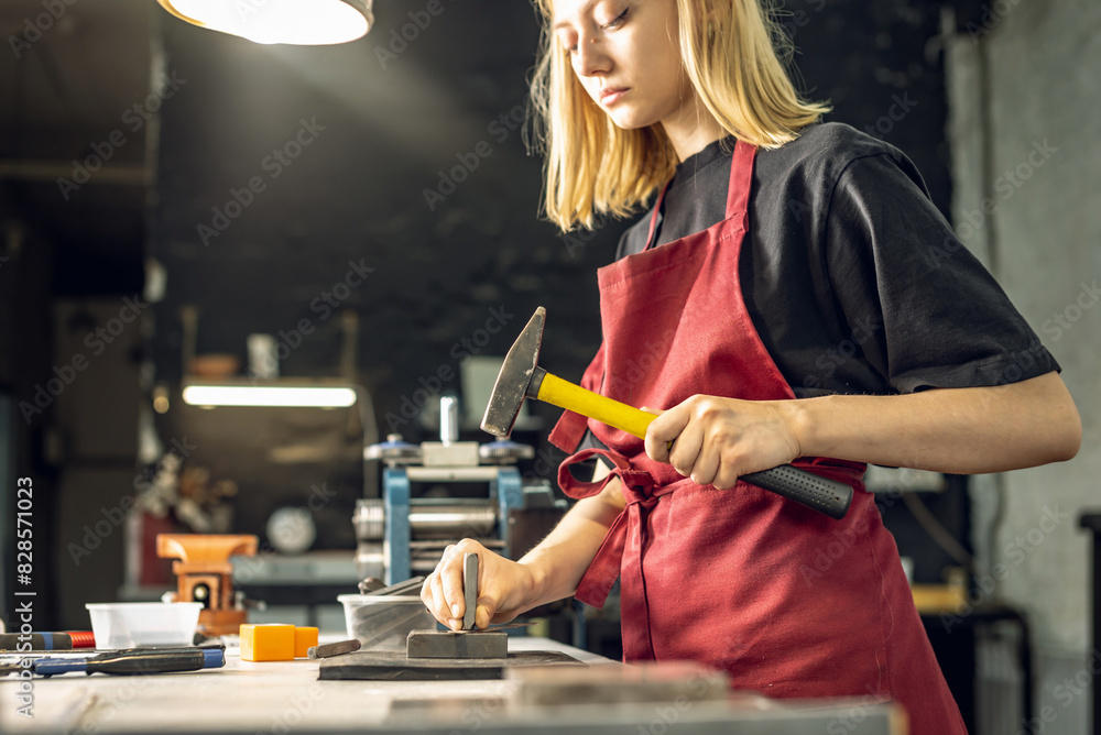 A jeweler uses a hammer to hammer out a unique ring design with a metal stamp. Craft in a jewelry workshop A jeweler uses a hammer to hammer out a unique ring design with a metal stamp. Craft in a jewelry workshop