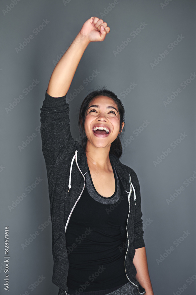 Fototapeta premium Woman, excited or celebration for fitness in studio with workout success or wellness achievement on podium. Pro athlete, sportswear or energy for winning or victory with confidence on grey background