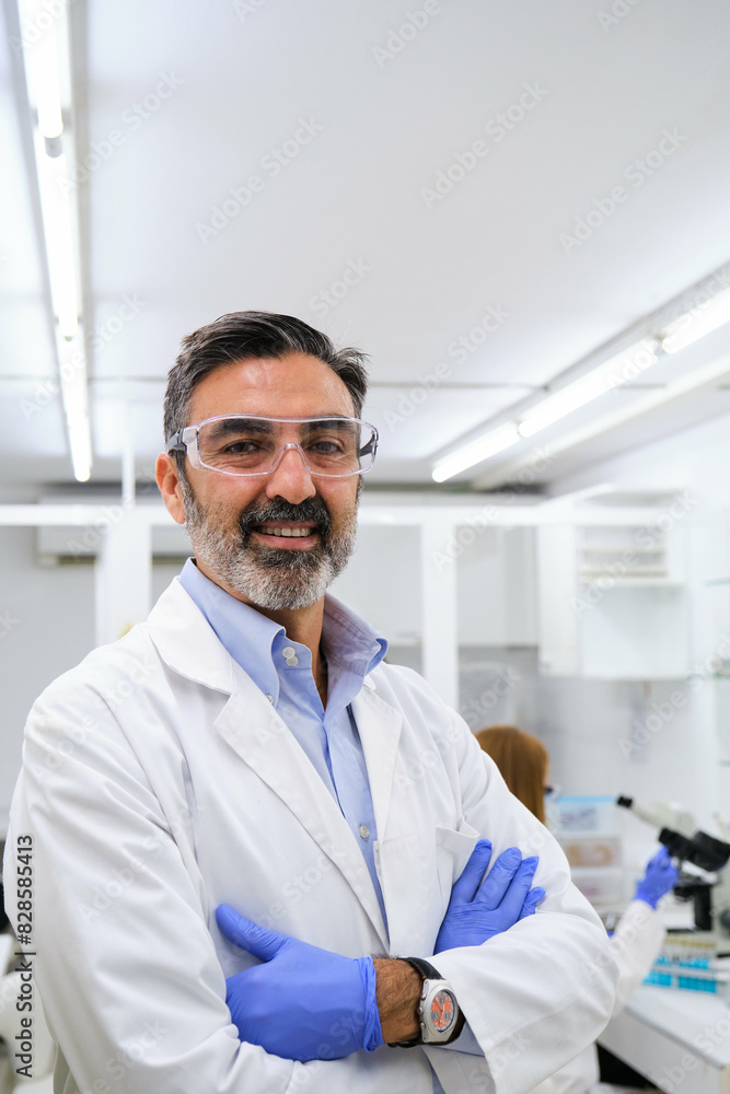 Portrait of a middle aged professional researcher with protective glasses and gloves smiling and looking at camera. Portrait of a middle aged professional researcher with protective glasses and gloves smiling and looking at camera.