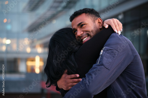 Latin man and a woman hug each other and smiling in a city. Happy Hispanic couple.