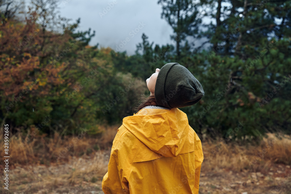 Lonely woman in a bright yellow raincoat standing in a vast field and gazing up at the sky Lonely woman in a bright yellow raincoat standing in a vast field and gazing up at the sky