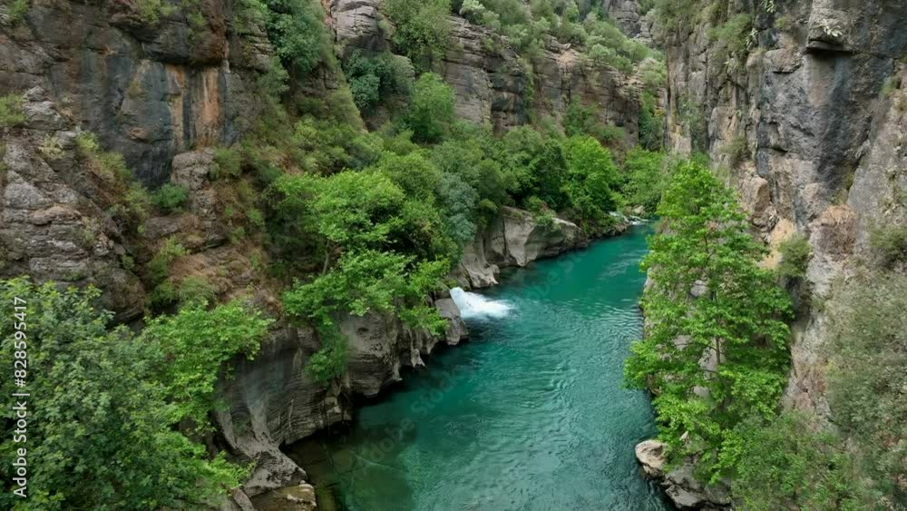 Turquoise river flowing through a lush, green canyon with steep rocky cliffs Turquoise river flowing through a lush, green canyon with steep rocky cliffs
