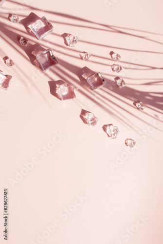 Ice cubes and palm leaves shadow on a pink background with contrasting shadows. Flat lay