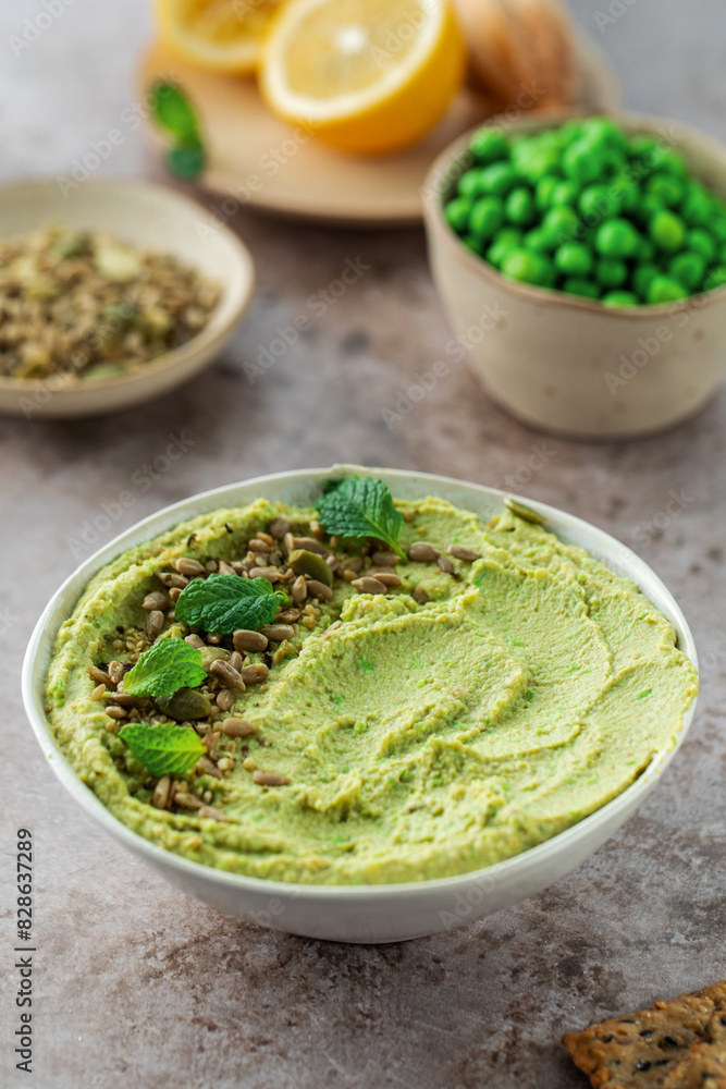 Hummus made of chickpeas, fresh green peas and mint, sprinkled with seeds