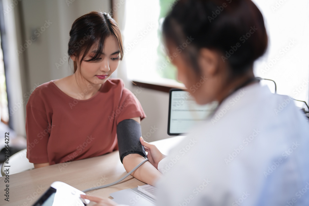 Asian psychologist women using digital sphygmomanometer to checking blood pressure and heart rate of female patient while giving to counseling about medicine and mental health therapy in clinic Asian psychologist women using digital sphygmomanometer to checking blood pressure and heart rate of female patient while giving to counseling about medicine and mental health therapy in clinic