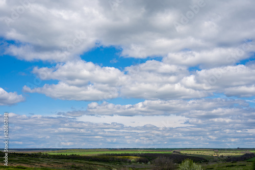 A beautiful scene of a blue sky with white clouds over a vast green field
