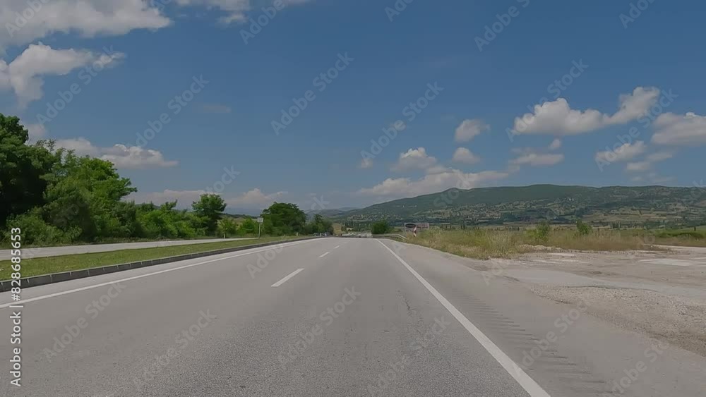 Road view on a summer day. Highways and landscape, palm trees and mountains, roadside and white road line markings. Road view on a summer day. Highways and landscape, palm trees and mountains, roadside and white road line markings.