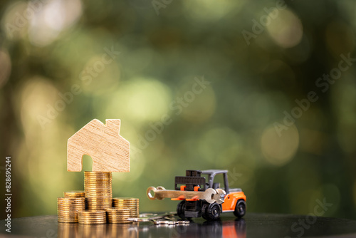 Home model put on the stack gold coin and forklift and and wrench a construction tool with working in the public park, Saving money and loan for renovation to real estate and house concept.
