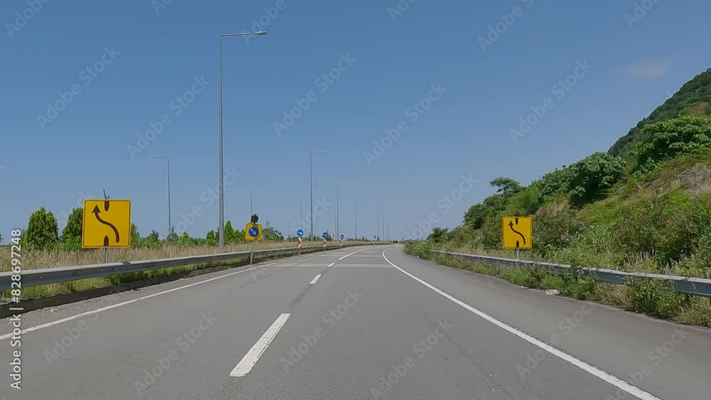 Road view on a summer day. Highways and landscape, palm trees and mountains, roadside and white road line markings. Road view on a summer day. Highways and landscape, palm trees and mountains, roadside and white road line markings.