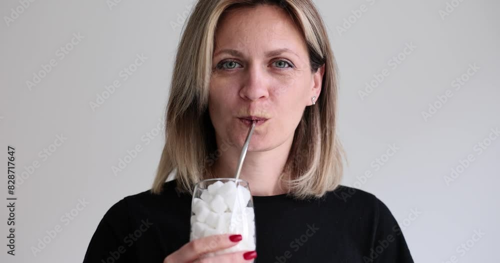 Portrait of beautiful woman drinking from glass of sugar with straw. Glass filled with sugar cubes Portrait of beautiful woman drinking from glass of sugar with straw. Glass filled with sugar cubes