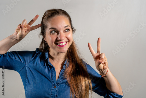 Mujer contenta haciendo el signo de la victoria con ambas manos. photo