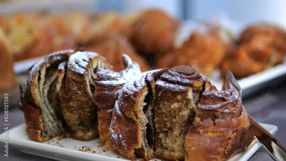 Freshly baked sweet buns Cinnabons cut into pieces on plate. Fragrant, fluffy buns perfect treat for those with sweet tooth. Sweet buns, sprinkled with powdered sugar, beckon with aroma of cinnamon. Freshly baked sweet buns Cinnabons cut into pieces on plate. Fragrant, fluffy buns perfect treat for those with sweet tooth. Sweet buns, sprinkled with powdered sugar, beckon with aroma of cinnamon.