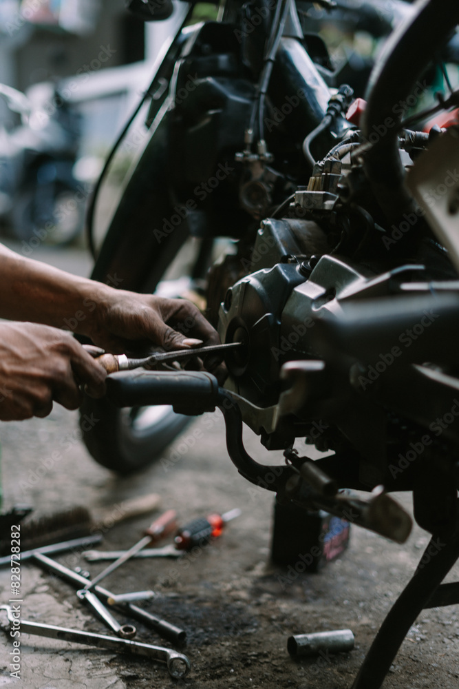 A motorcycle mechanic inspecting a damaged engine A motorcycle mechanic inspecting a damaged engine