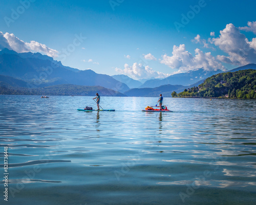 Paddle boarders on Annecy lake with mountains in the background.