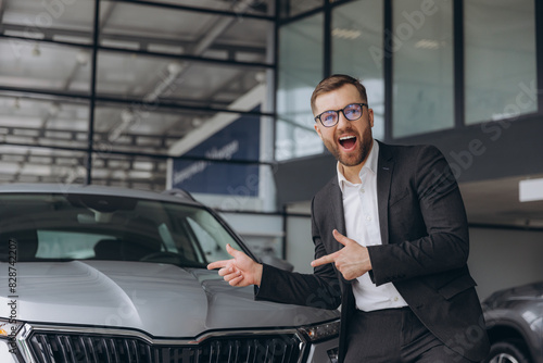 Yes, that's my new car! Customer in car dealership. Happy bearded man new car owner raises his hands up © anatoliycherkas