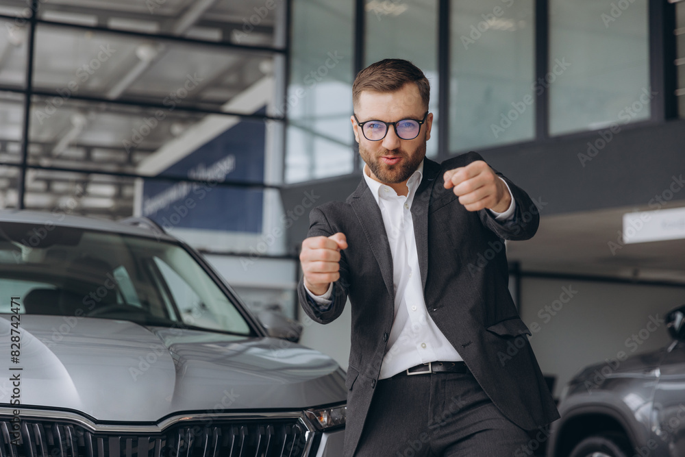 Yes, that's my new car! Customer in car dealership. Happy bearded man new car owner shows driving a car Yes, that's my new car! Customer in car dealership. Happy bearded man new car owner shows driving a car