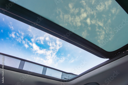 View of a blue sky and clouds through an open car sunroof, emphasizing freedom and travel.