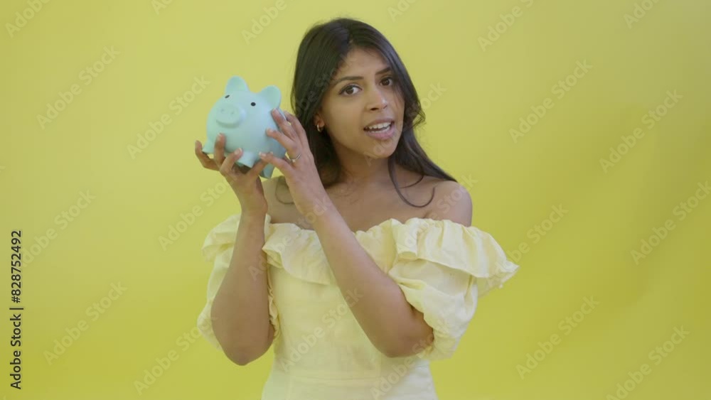 worrying Indian woman holding shaking piggy bank, saving up for a rainy day, investment, savings, currency, deposit. worrying Indian woman holding shaking piggy bank, saving up for a rainy day, investment, savings, currency, deposit.