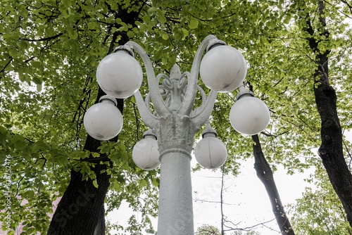 old white six-pointed street lamp stands in the park.