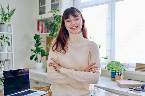 Foto Portrait of smiling female student, 19,20 years old, looking at camera, in home