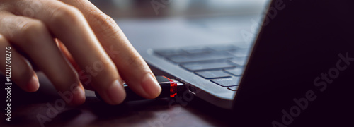 Hand holding usb flash drive with connecting to laptop at wooden table photo