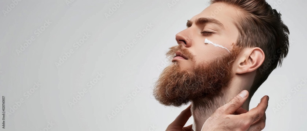 Closeup of a bearded man applying cream on his face, showcasing skincare and grooming routine against a grey background. Closeup of a bearded man applying cream on his face, showcasing skincare and grooming routine against a grey background.