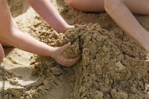 Summer background. Childrens hands grasping wet sand on a Mediterranean beach, evoking feelings of summer vacation and carefree play. The simple joy of touching the sand is captured in this scene