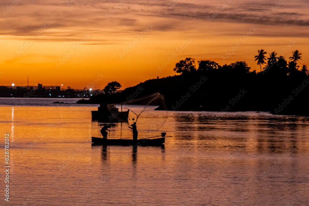 Silhoette of fishermen casting cast net at dawn