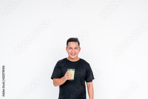 A cheerful middle aged Asian man smiles as he drinks a refreshing glass of lemonade, set against a white background. photo