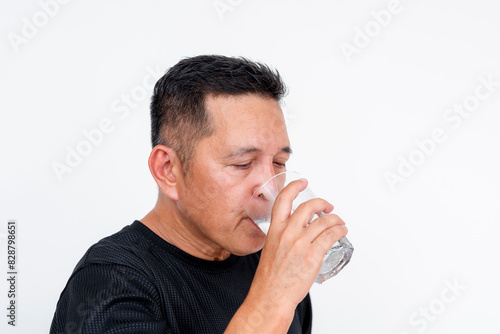 Asian man drinking a full glass of water to quench his thirst. Having a healthy drink , action shot. © Mdv Edwards
