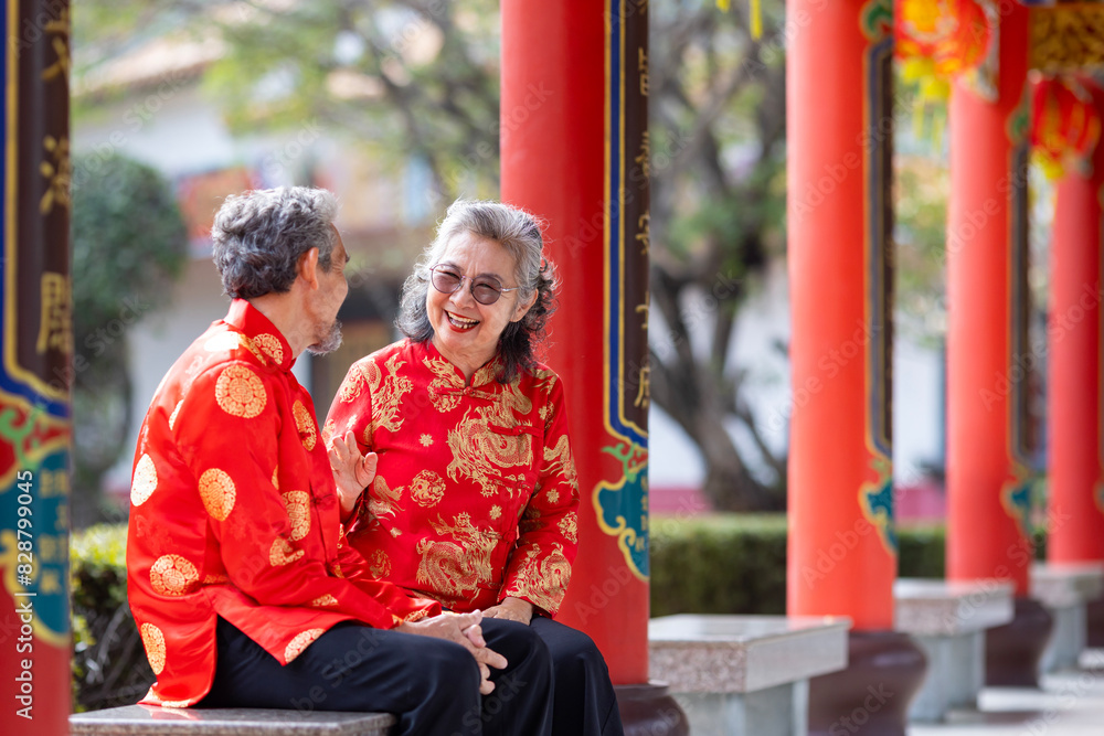 Obraz premium Asian marriage senior couple in cheongsam qipao dress is talking to each other inside the temple during Chinese new year for family and relative gathering in hometown concept
