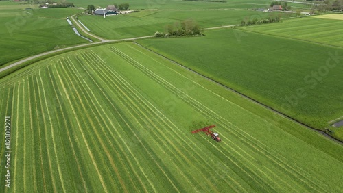 Aerial View: Tractor Shaking Grass on the Field in Farmland during Harvesting (ID: 828802271)
