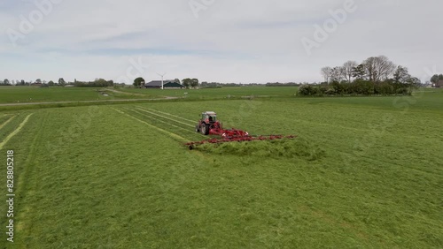 Aerial View: Tractor Shaking Grass on the Field in Farmland during Harvesting (ID: 828805218)
