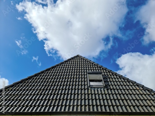 Open roof window in velux style with black roof tiles.