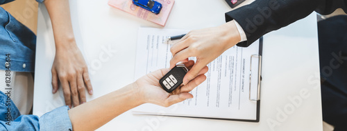 Concept car rental service. Close up view hands of agent giving car key to client that rent a vehicle in rental office. photo