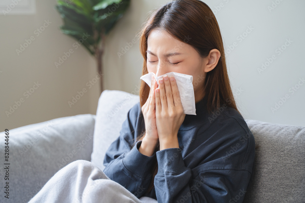 Sick at home concept. Woman sneezing on the sofa in winter season. Sick at home concept. Woman sneezing on the sofa in winter season.