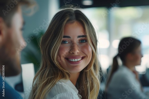 Happy young businesswoman looking behind and her colleagues working at office
