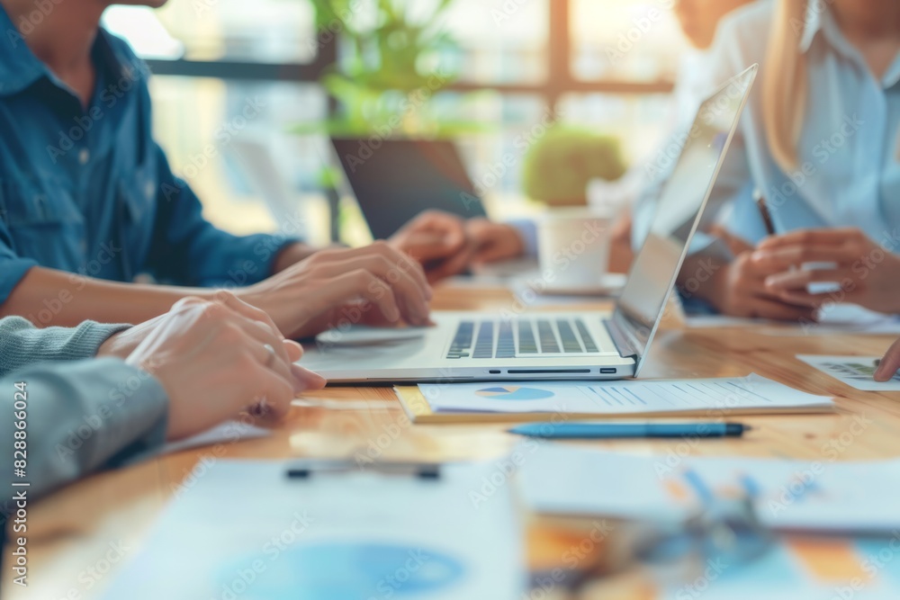Professional Team Collaborating in Modern Office Environment with Laptops and Financial Charts Professional Team Collaborating in Modern Office Environment with Laptops and Financial Charts