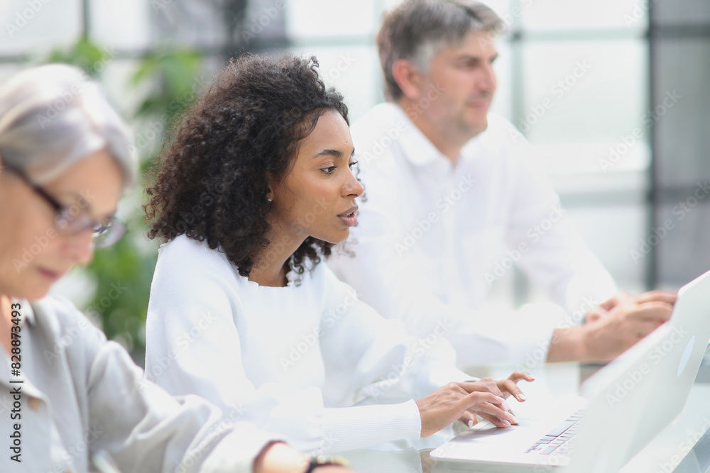 Fototapeta premium Black woman sitting at a table and using a computer