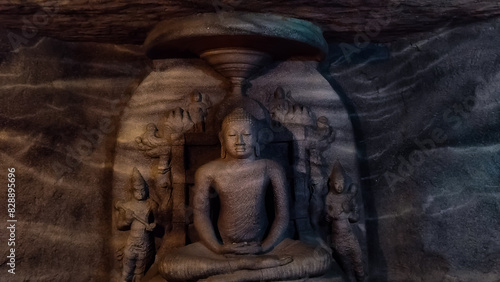 A close-up view of a historic Buddha statue carved inside a rock cave.