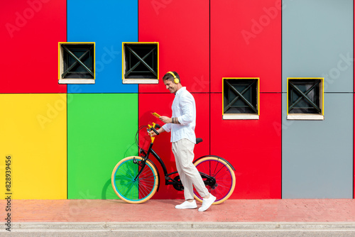 Fashionable man with a colorful bike against a vibrant wall photo