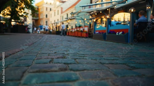 Cobblestone street with outdoor cafes and charming lighting in the city at dusk photo