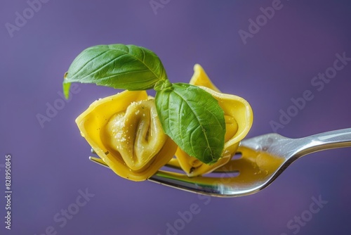 A fork holding a delectable tortellini and a fresh basil leaf with a soft focus purple background to highlight the dish