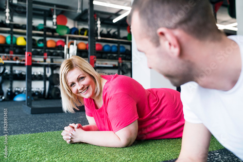 Fotografie Overweight woman exercising on gym mat in gym