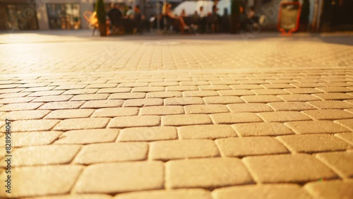 A sunny day on a cobblestone street with a group of people enjoying the warm sunlight photo