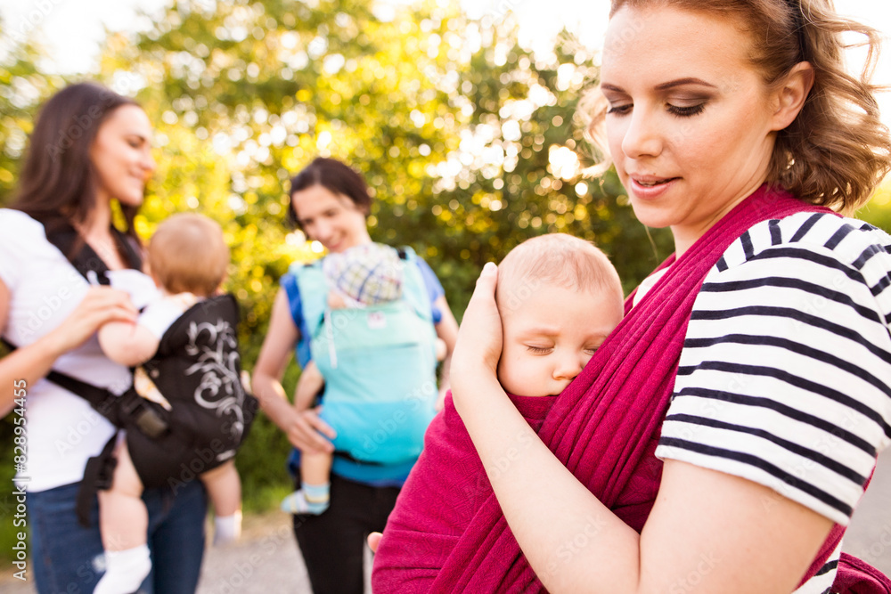 Mothers carrying babies in carriers, slings or wraps. Babywearing. Mothers carrying babies in carriers, slings or wraps. Babywearing.