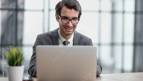 Smiling business man working on laptop at office.